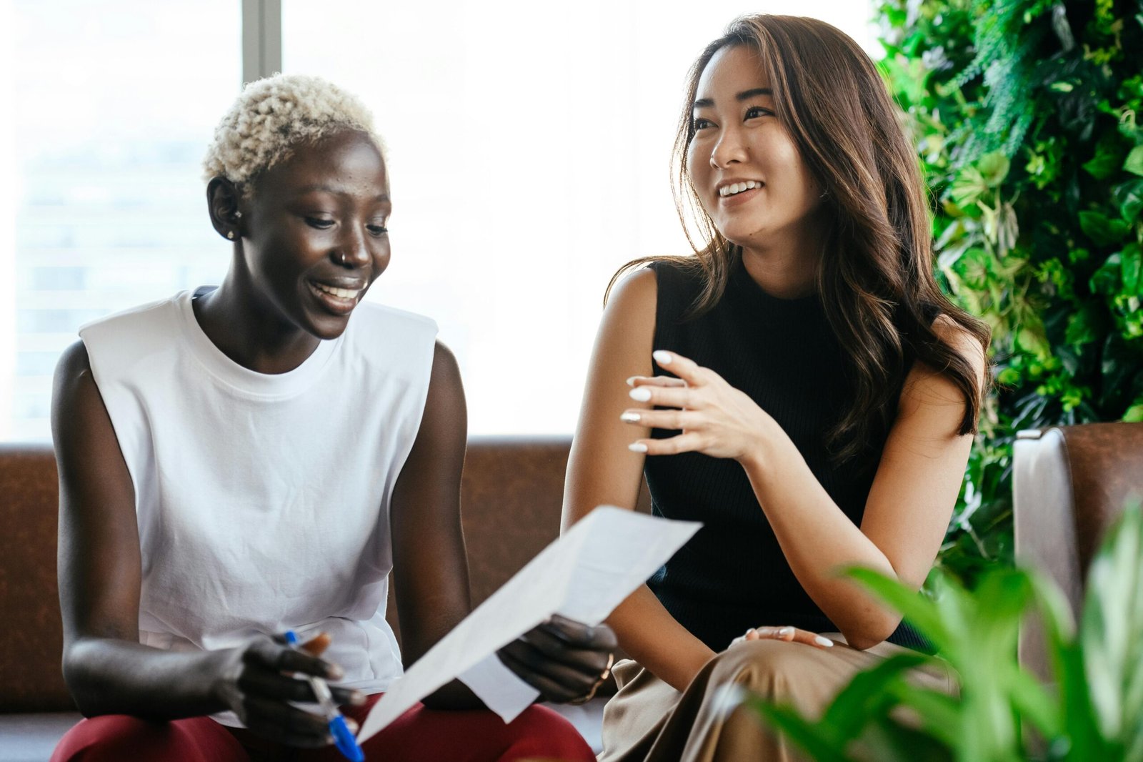 Two young female business owners confidently going through paperwork in a bright and airy office.